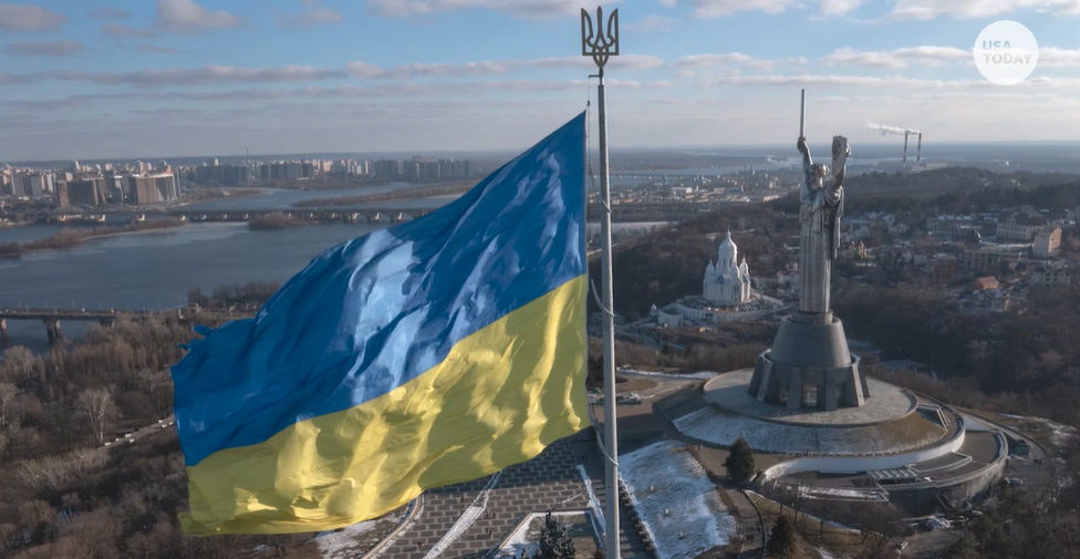Ukrainian flag flies on a pole overlooking a large city