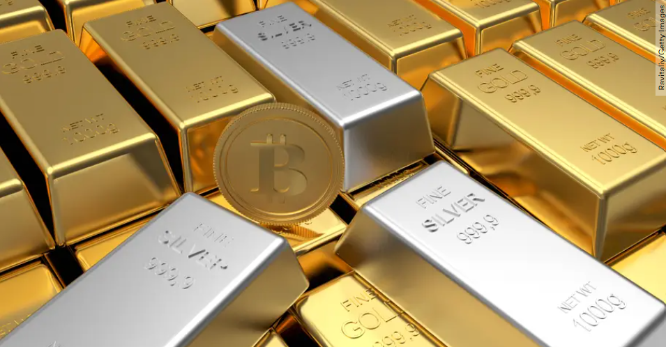 Bars of gold and silver sit with a bitcoin standing up among them