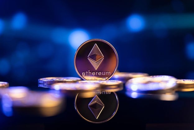 The Ethereum coin sits among other coins laying on a reflective surface