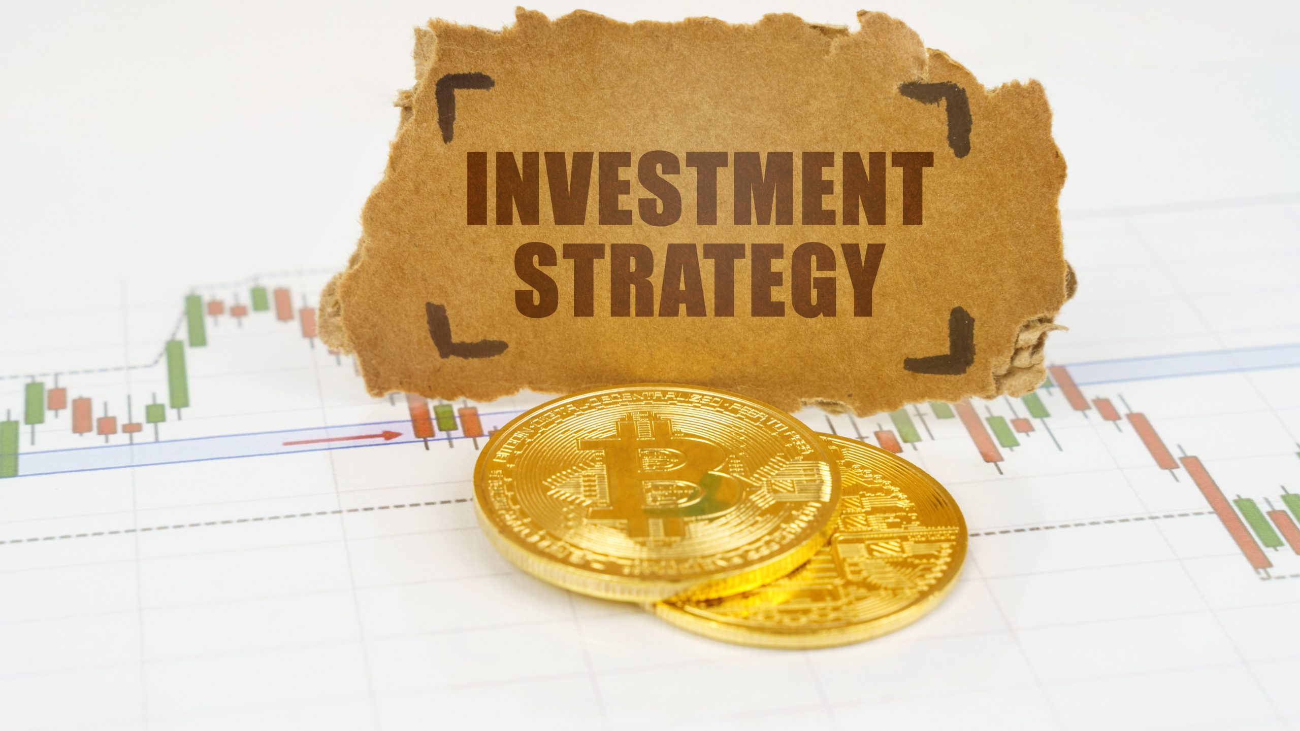 "Investment Strategy" text on cardboard above two physical bitcoins (Bitcoin in IRA)